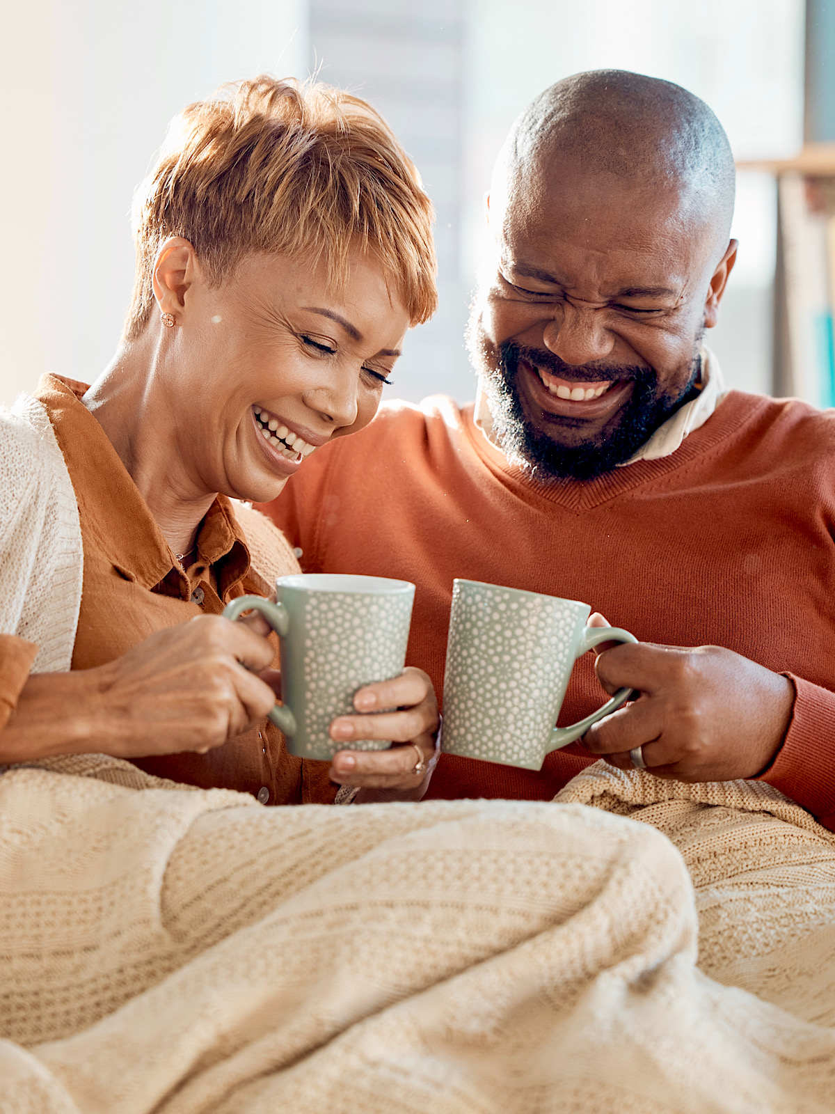 Couple In Living Room Smiling, Drinking Tea Cups